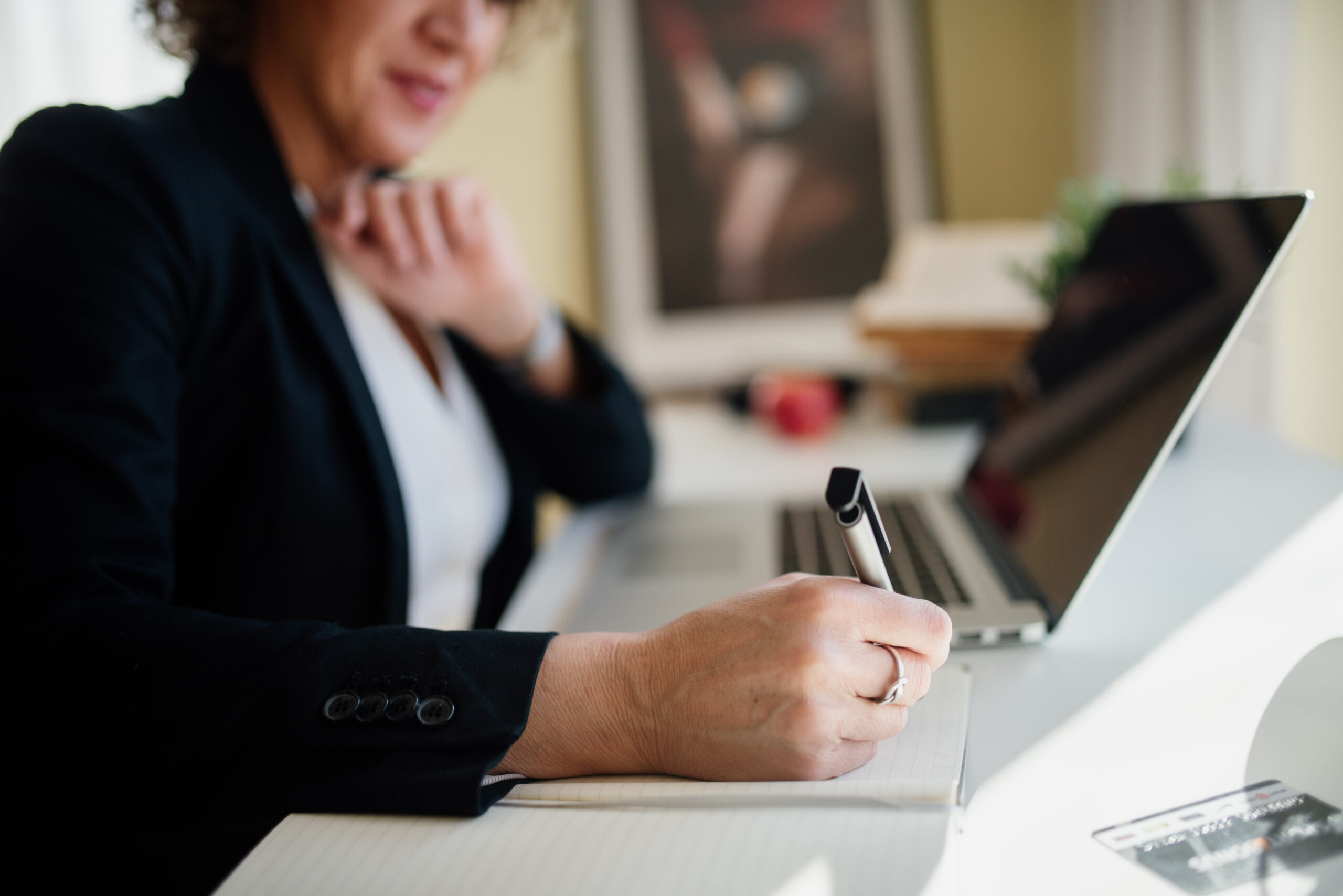 Business professional taking notes at an office desk during a meeting