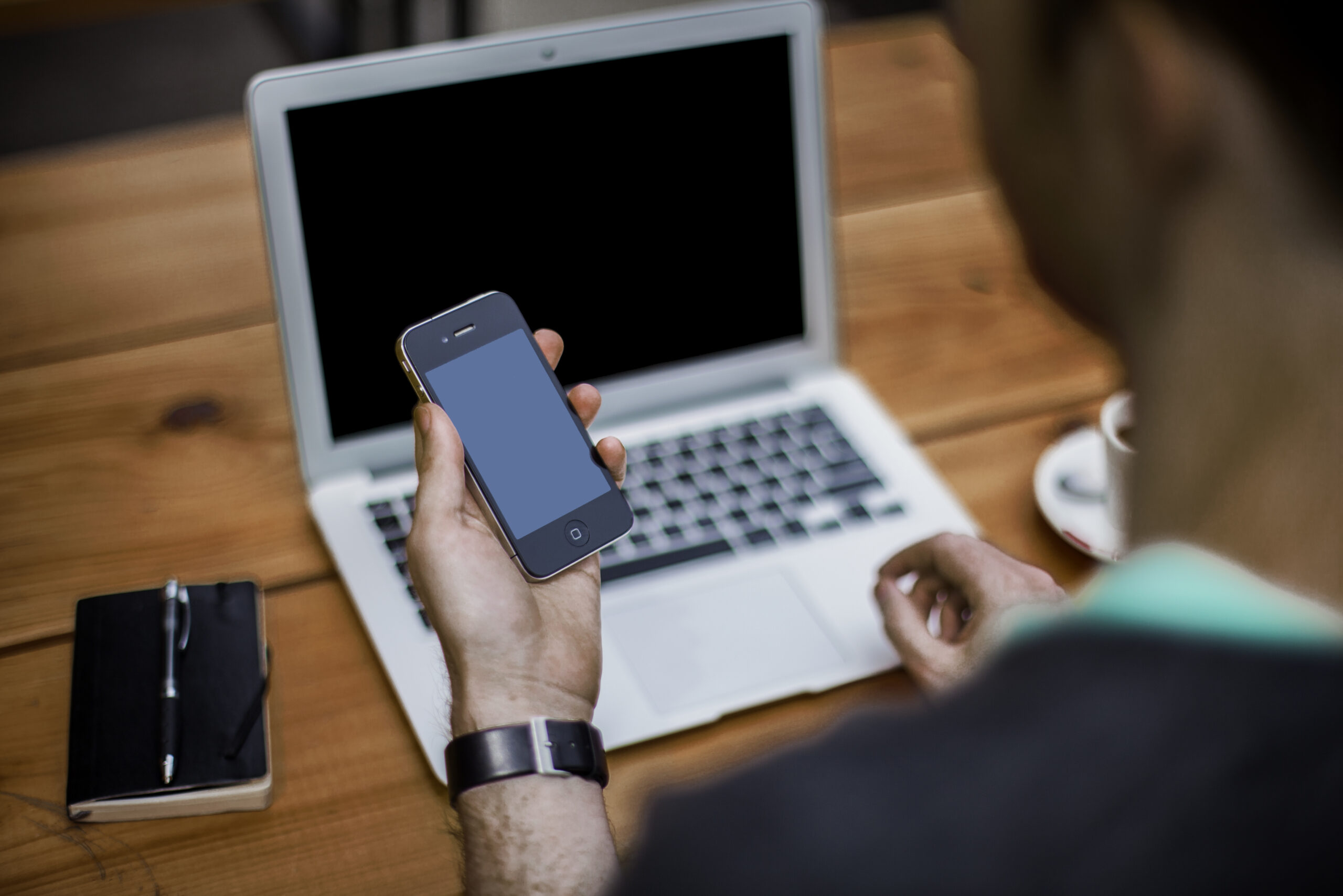 Person using a smartphone beside an open laptop