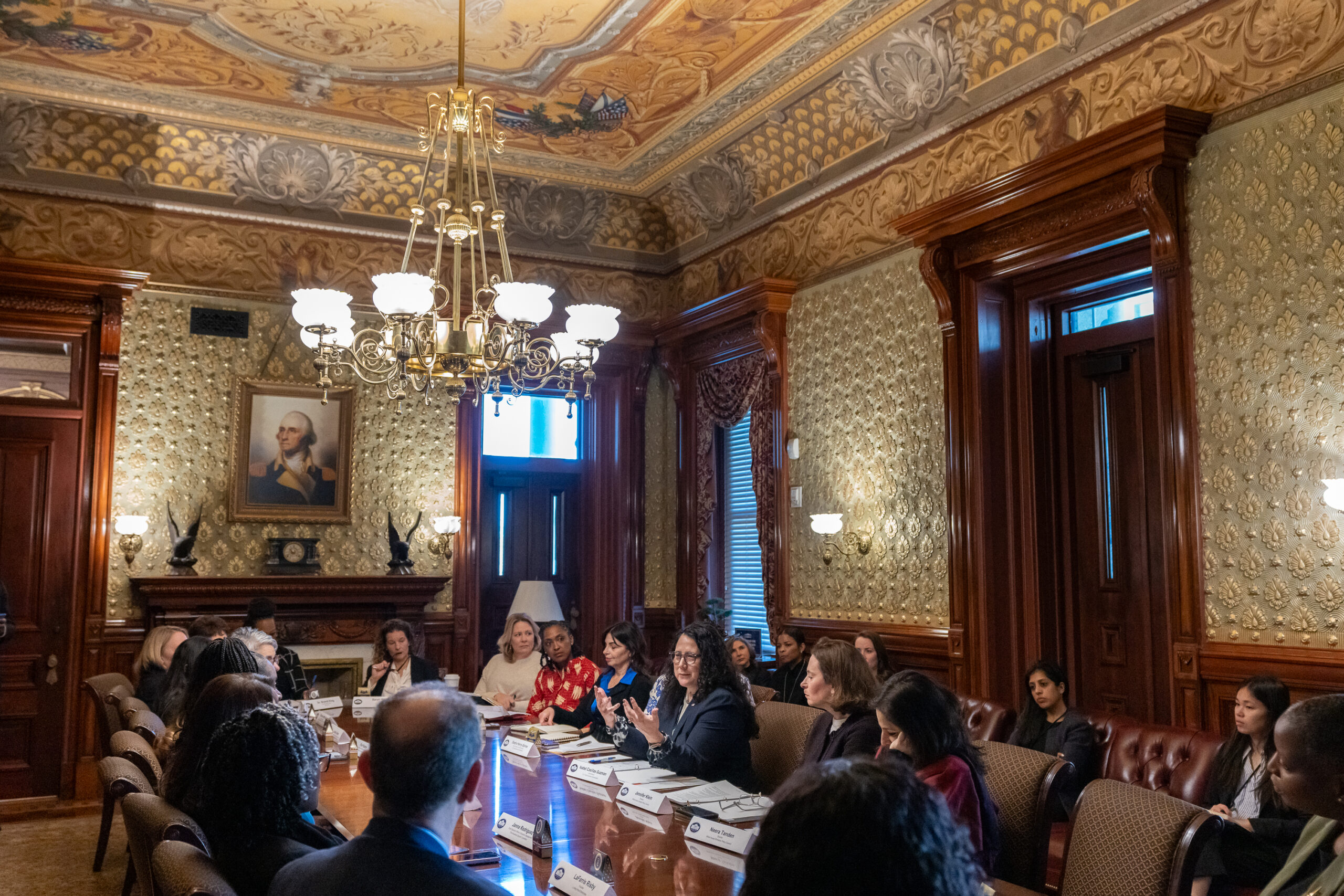 Business and organization leaders seated around a conference table in a working meeting